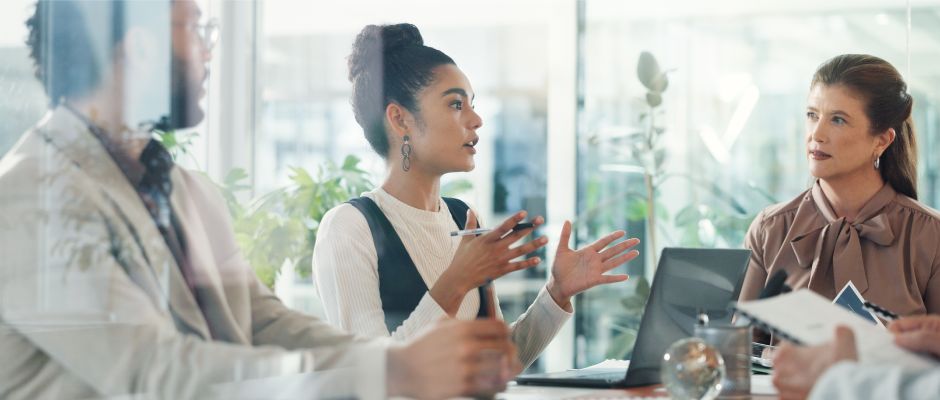 Woman gesturing while speaking during a meeting with colleagues.
