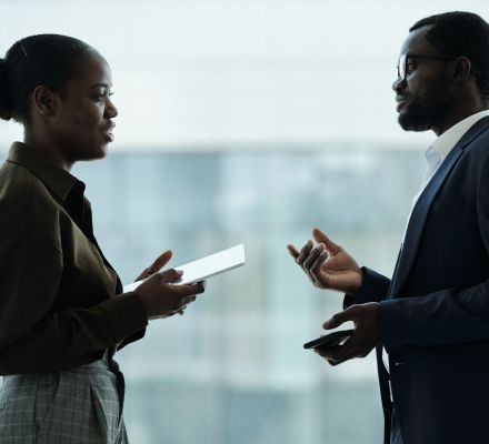 Man and woman having a tense discussion in an office hallway.