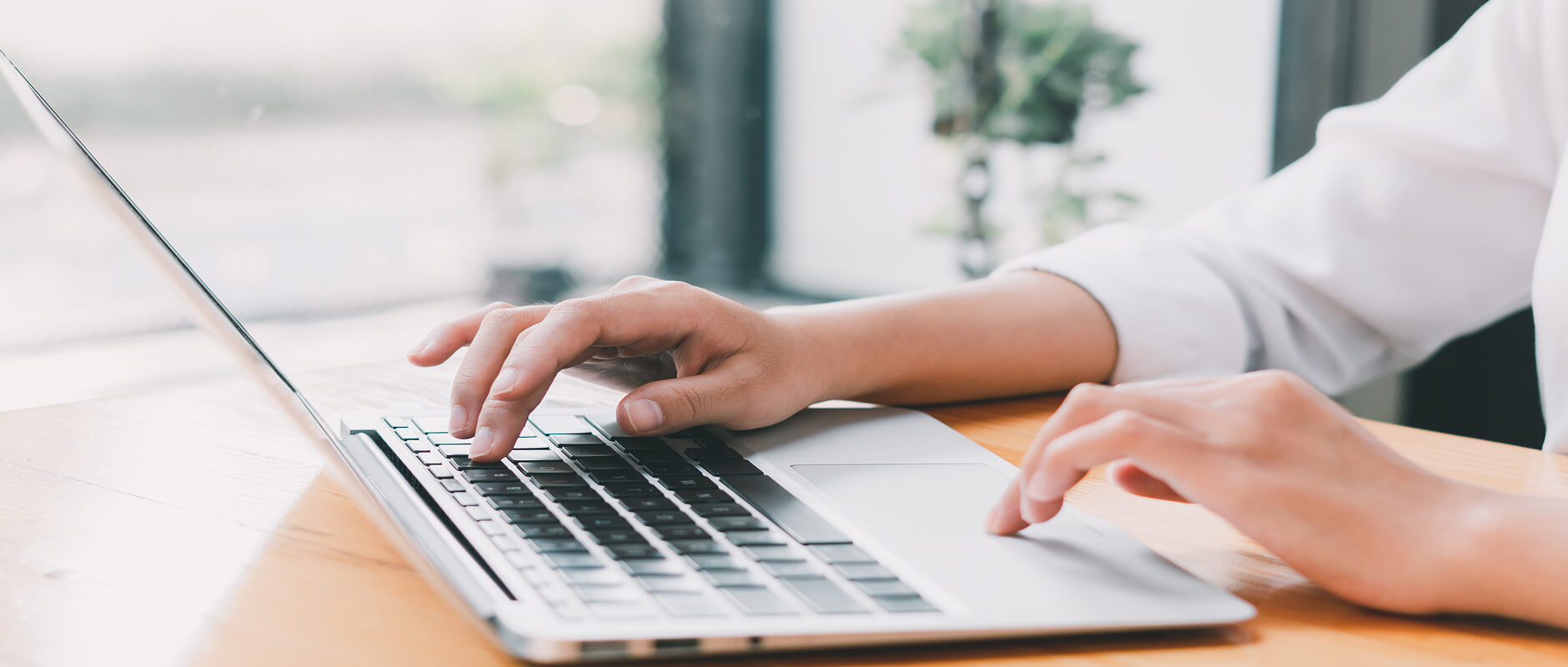 Close-up of hands typing on a laptop keyboard.